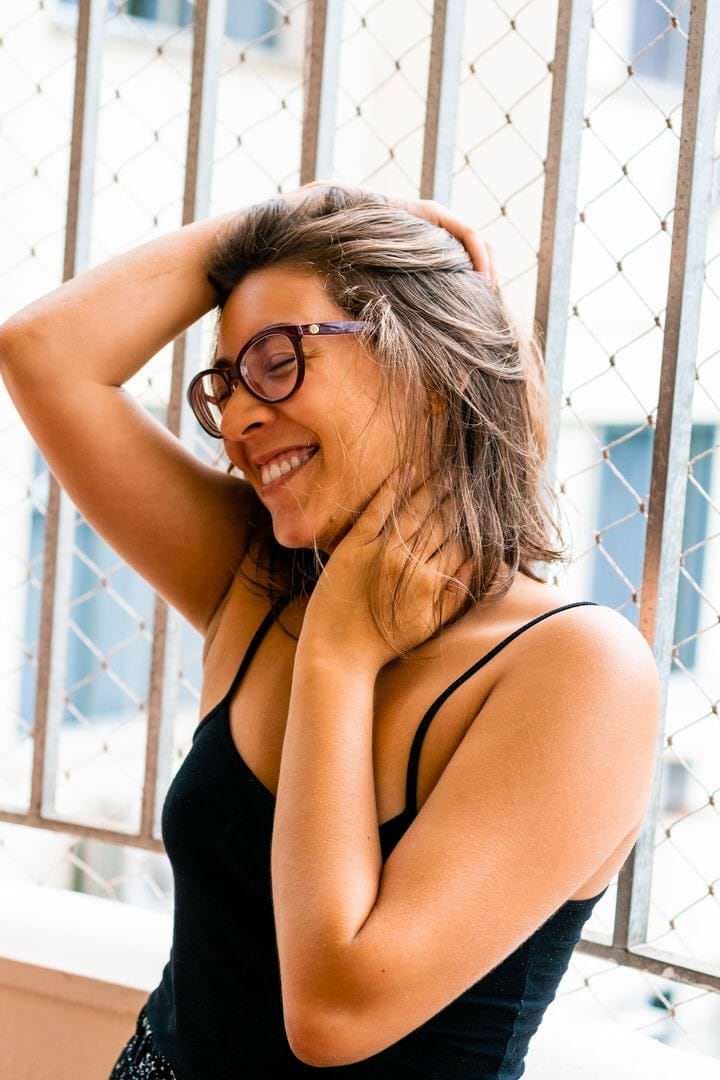 Uma mulher com óculos está em um ambiente com fundo de malha.