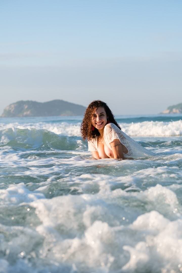 Uma mulher está nadando em um lago, com colinas e céu no fundo.