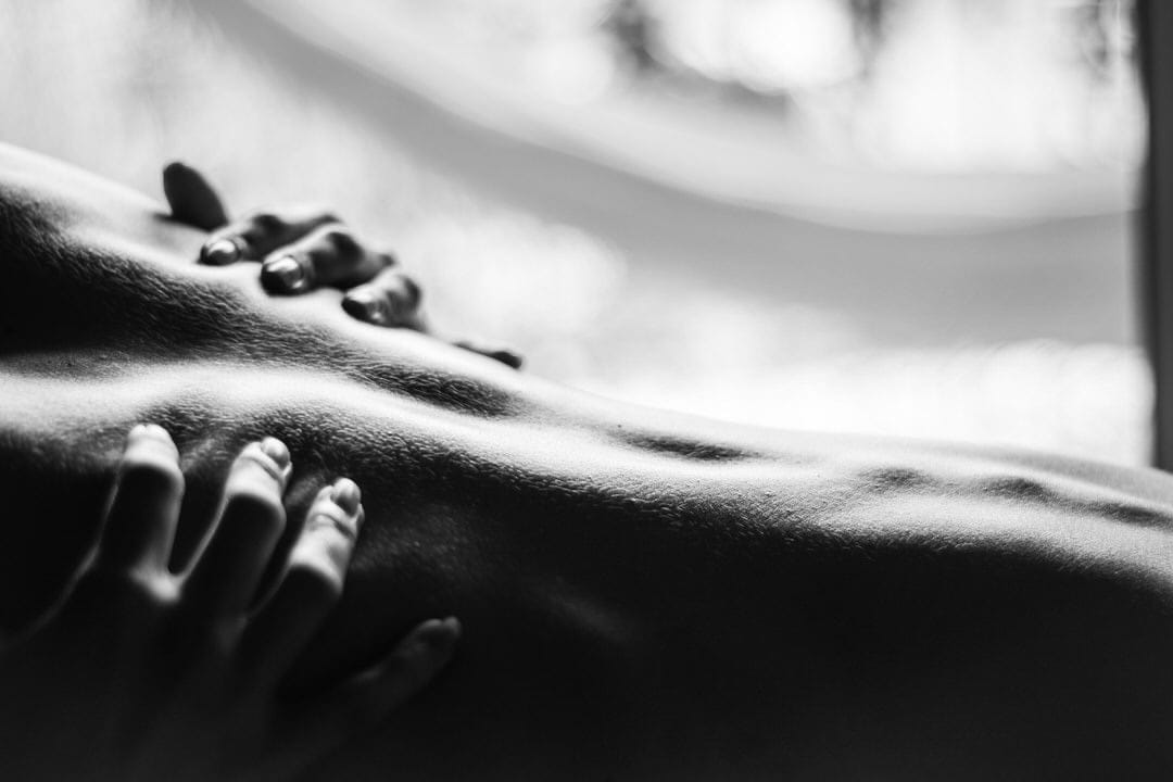 Um corpo humano em um cômodo com luz natural sussurrando por uma janela parcialmente aberta.