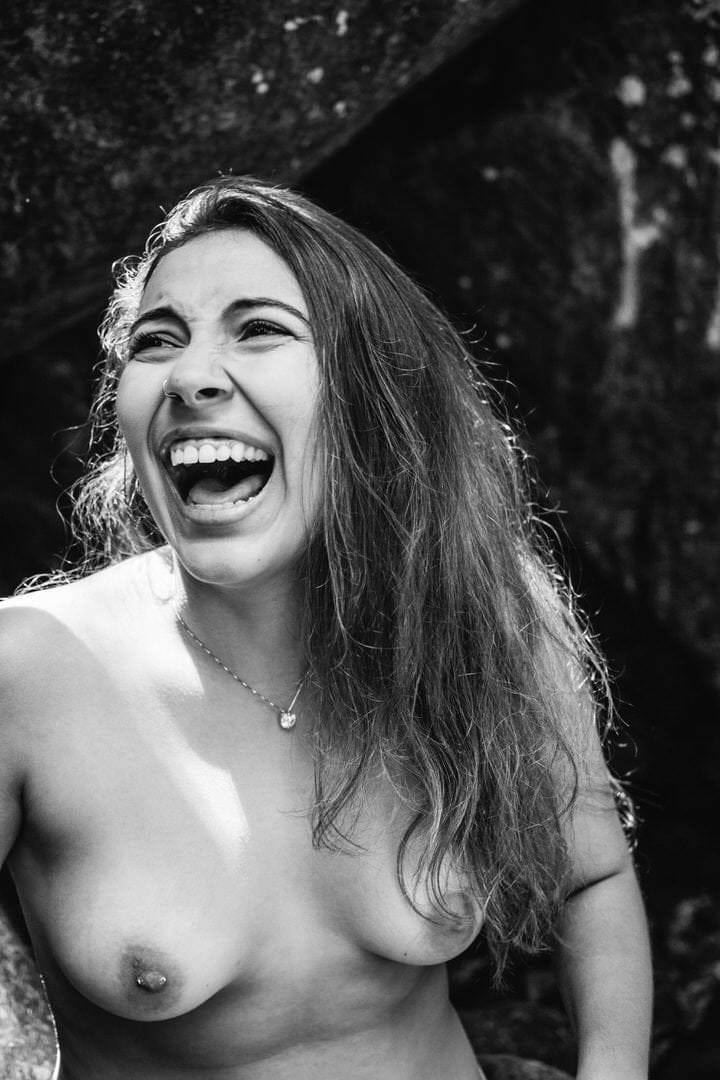 Uma mulher sorrindo em um ambiente escuro, com luz suave vindo de um canto.